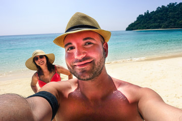 Handsome hipster couple making selfie on paradise beach 