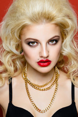 Portrait of beautiful blonde glam rocker woman on orange background. Closeup of Beauty Woman face make up. Bright make-up with sexy red lips and perfect skin