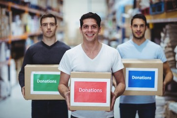 Volunteers smiling at camera holding donations boxes