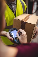 Woman signing on device to delivery parcel