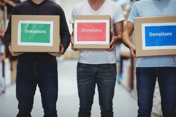 Volunteers smiling at camera holding donations boxes
