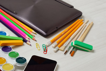 Naklejka premium School or student supplies with closed slim notebook and smartphone on a white wooden table surface