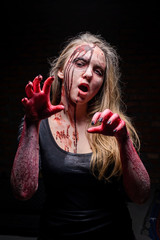 Scary bloody zombie girl on black background. Horror. Halloween/Scary bloody zombie girl looking at the camera against black background © nesterenko_max