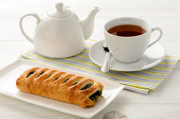 Puff pastry with spinach and cup of tea on the wooden background.
