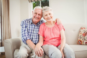 Senior couple sitting on sofa and smiling