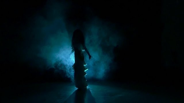 Beautiful exotic belly dancer girl, shaking her hips, on black, slow motion, silhouette, smoke