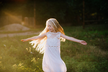 Portrait of a baby girl spinning in a field in sunset light, life style