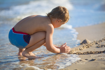 baby boy playing on the beach in the sand