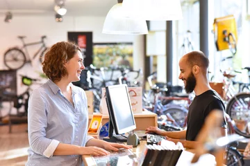 Foto op Plexiglas Lifestyle Shopping - junge Frau kauft in einem Fahrradladen ein, Beratung durch Verkäufer © industrieblick