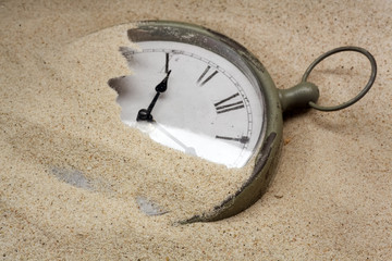 Time concept with a cklock on the sand