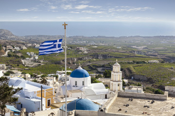 Rooftop view of Pyrgos in Santorini with greek flag