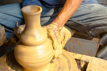 Hands of making clay pot on the pottery wheel ,select focus, close-up.