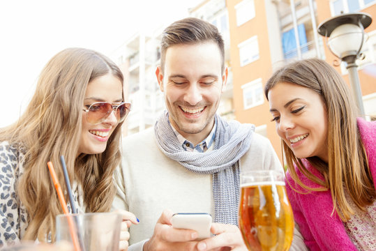 Close-up of three young cheerful people drinking beer outdoors