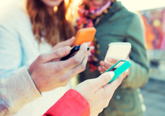 close up of friends with smartphones outdoors