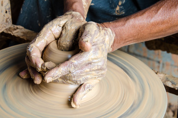 Hands of making clay pot on the pottery wheel ,select focus, close-up.