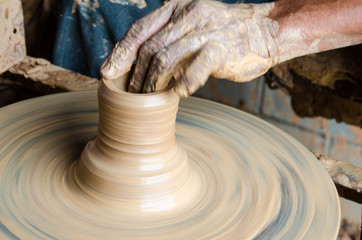 Hands of making clay pot on the pottery wheel ,select focus, close-up.