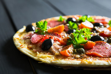 Pizza with salami, olives and herbs