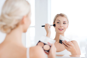 Obraz na płótnie Canvas woman with makeup brush and foundation at bathroom