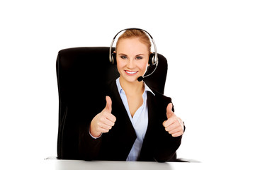 Smiling phone operator in headphones sitting  behind the desk