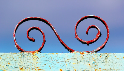 Detail of old metal decorative element on rusty painted fence