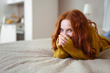 frau liegt auf dem bett und schaut lachend in die kamera