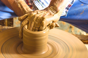 Hands of making clay pot on the pottery wheel ,select focus, close-up.