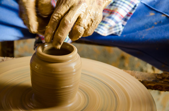 Hands of making clay pot on the pottery wheel ,select focus, close-up.