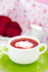 Red Ukrainian borsch soup with sour cream in a white plate.