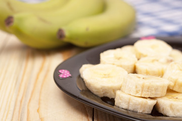 green banana with slices on wooden background