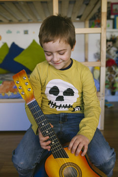 Child playing guitar in the room