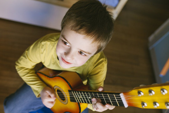 Child playing guitar in the room