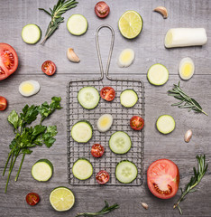 Healthy foods, cooking and vegetarian concept sliced cucumbers, zucchini, onion, lettuce, rosemary, tomatoes, parsley on wooden rustic background top view close up