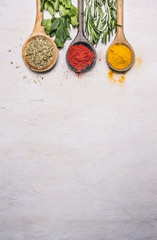 colorful spices in a wooden spoon with herbs, tandoori, oregano, curry border ,place for text  on wooden rustic background top view close up