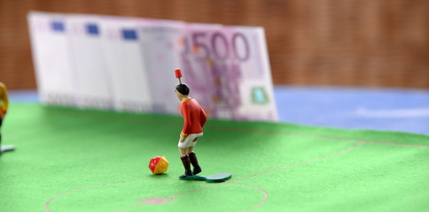 Tipp Kick, Fußballspielfigur mit Geldscheinen im Hintergrund