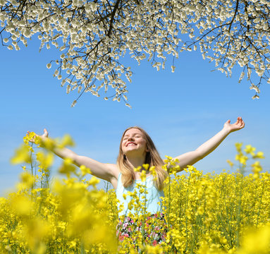 Young happy woman on blooming rapeseed field in spring