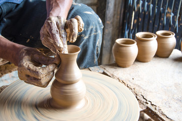 Hands of making clay pot on the pottery wheel ,select focus, close-up.