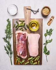 raw duck breast with rosemary, parsley, pepper, salt and oil, on a cutting board on wooden rustic background top view close up