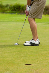 Fototapeta na wymiar golfer putting on green, view from legs down