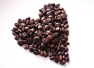 Grains roasted coffee in the shape of heart on  white plate