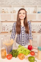 Portrait of housewife in the kitchen with vegetables and spaghet