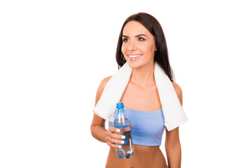 Attractive sportswoman with towel holding a bottle with fresh wa