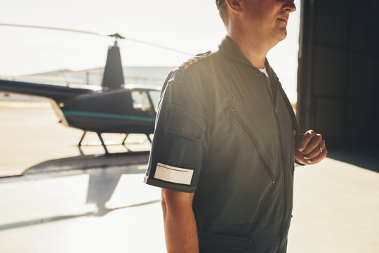 Professional pilot in uniform standing in airplane hangar