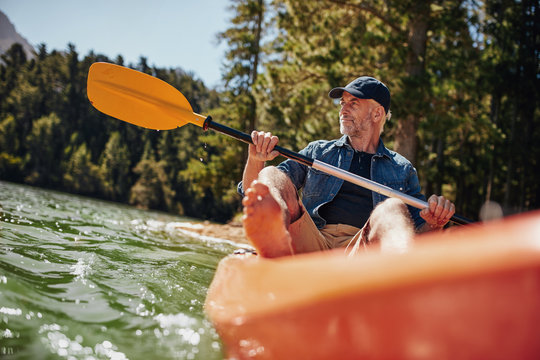 Mature Man Paddling A Kayak