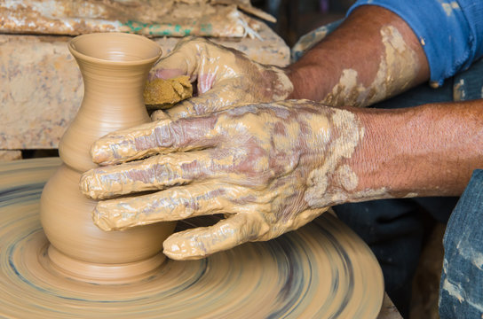 Hands of making clay pot on the pottery wheel ,select focus, close-up.