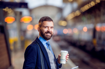 Hipster businessman with coffee cup at the train station