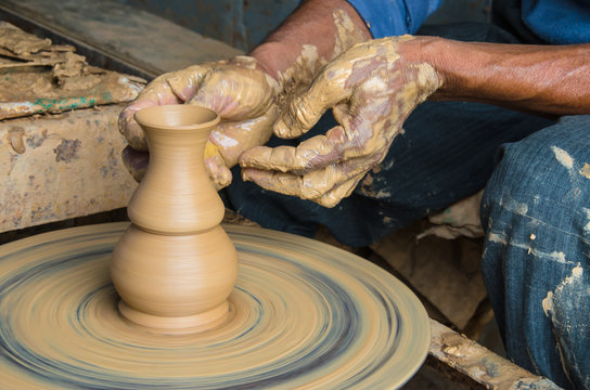 Hands of making clay pot on the pottery wheel ,select focus, close-up.