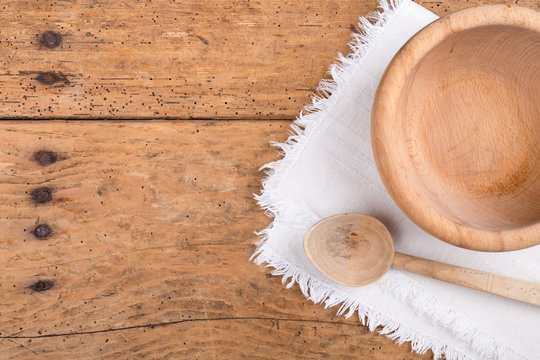 Wooden bowl, spoon and tablecloth on a rustic wooden table
