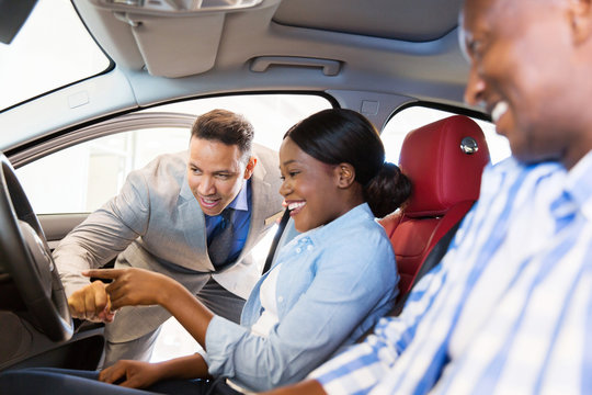 Salesman Showing New Car To African Couple