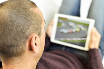 young man watching a car race in his tablet