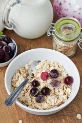 Healthy breakfast - bowl of oat flake, berries and fresh milk on wooden background 